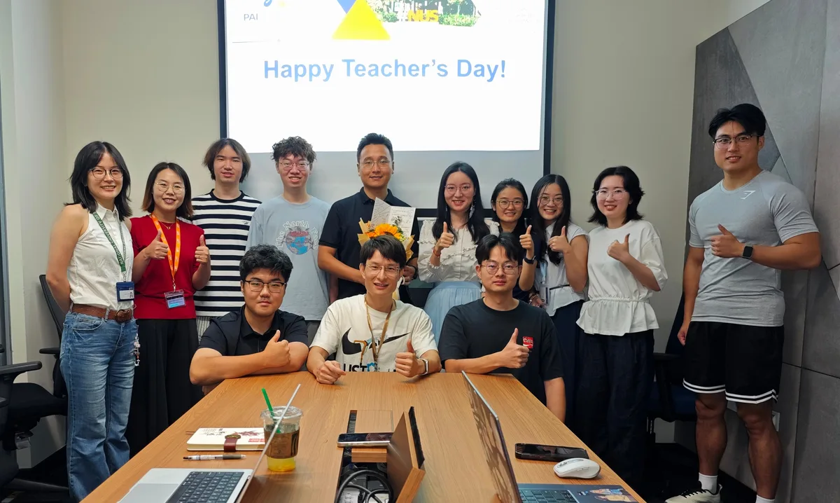 PAI Lab team gathered in front of a screen reading Happy Teacher's Day!